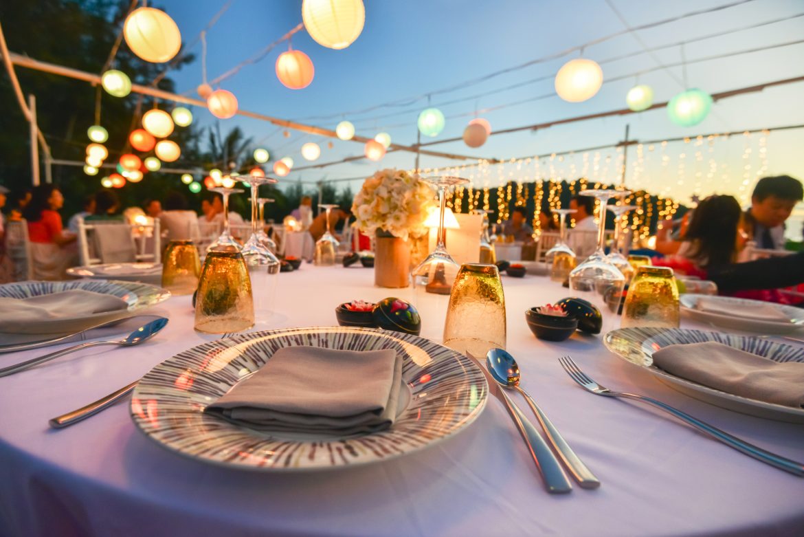 Elegant outdoor dinner table setup with candles, flowers, and colorful lanterns, perfect for home catering events