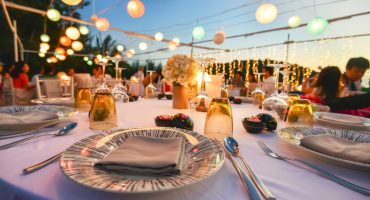 Elegant outdoor dinner table setup with candles, flowers, and colorful lanterns, perfect for home catering events