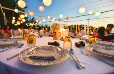 Elegant outdoor dinner table setup with candles, flowers, and colorful lanterns, perfect for home catering events